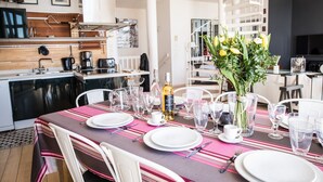 Un comedor moderno con una mesa dispuesta para cuatro, una cocina al fondo y una escalera de caracol.