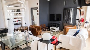 Una sala de estar moderna con una mesa de centro de vidrio, sofás de cuero, un televisor de pantalla plana y una unidad de estanterías empotrada.