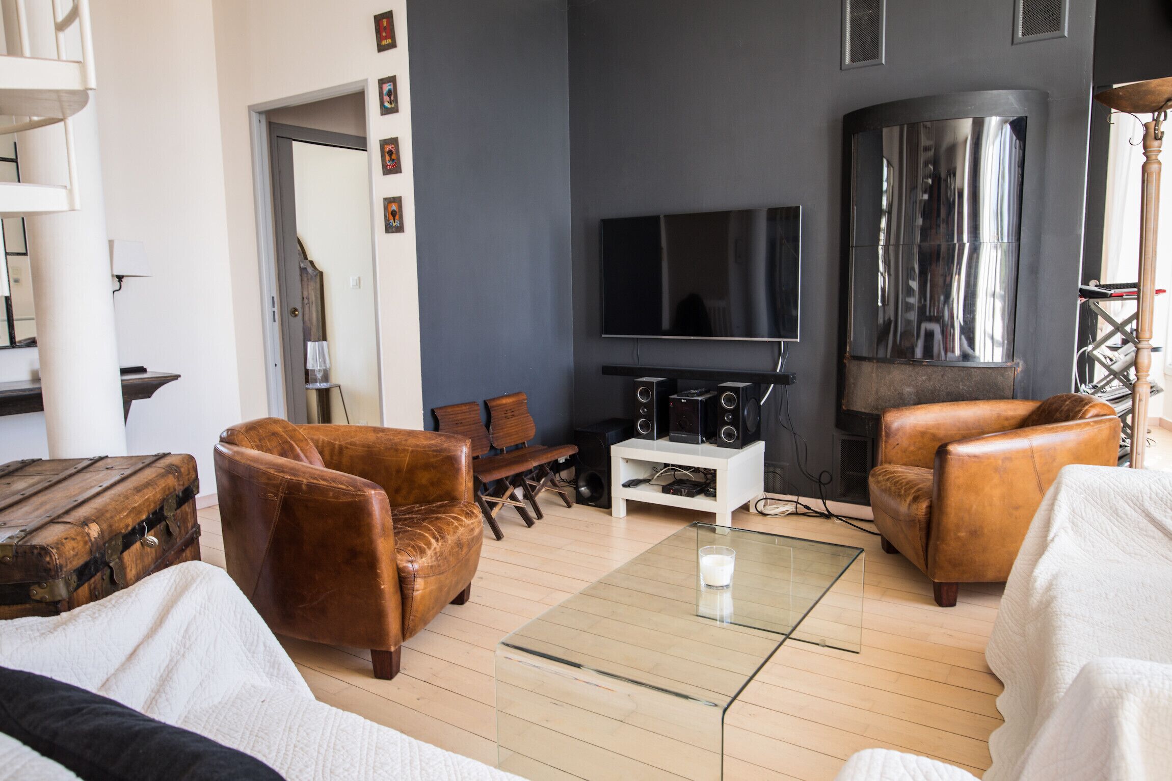 Una sala de estar moderna con sofás de cuero, una mesa de centro de vidrio, un televisor de pantalla plana y una chimenea.