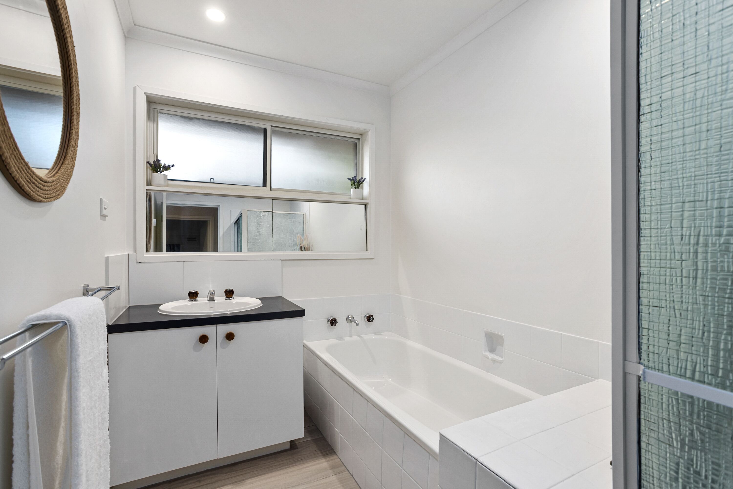 A modern bathroom with a white sink, vanity, and bathtub.