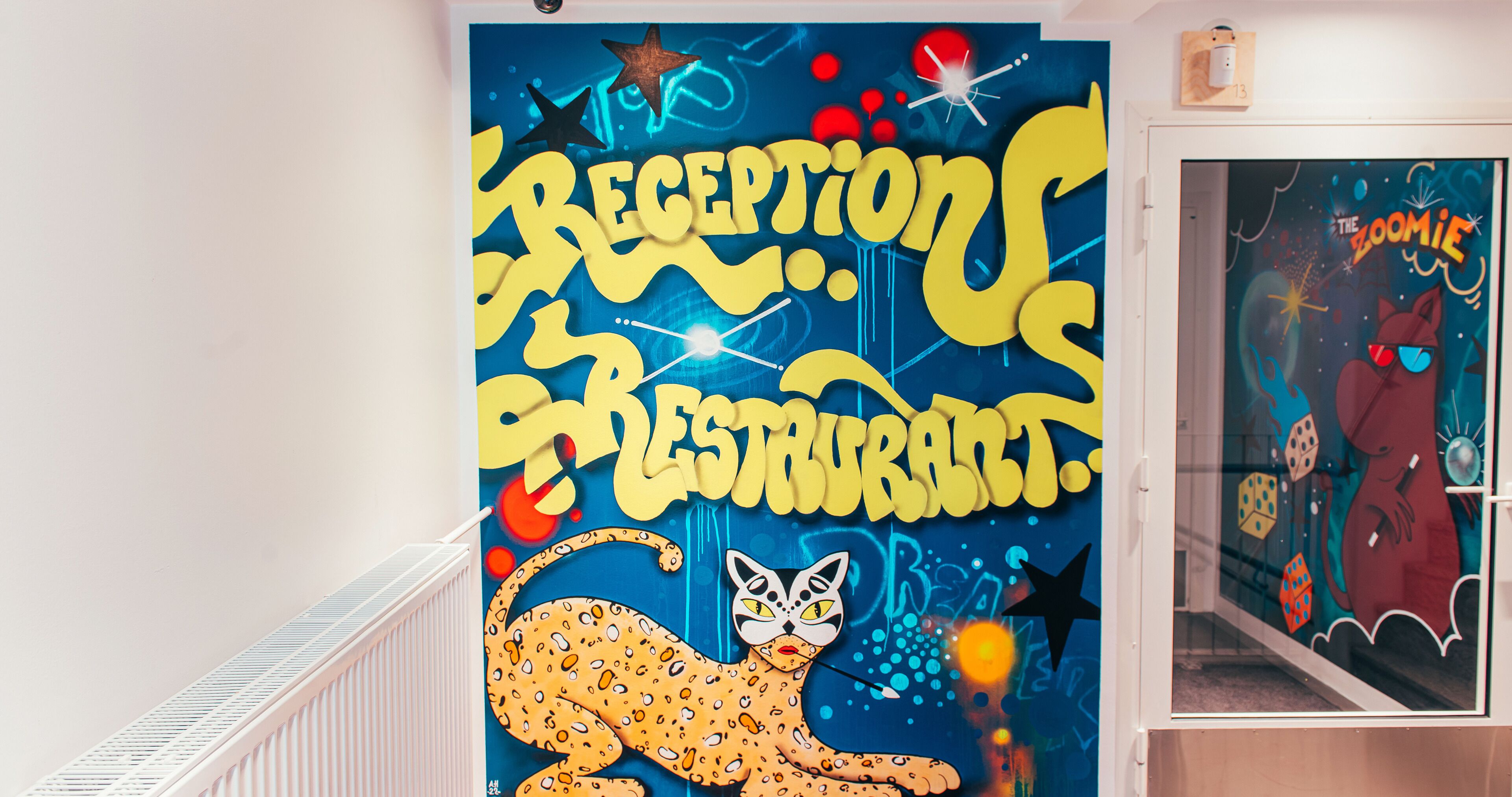A wall with a large, colorful mural featuring a cat and the words "RECEPTION RESTAURANT."