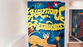 A wall with a large, colorful mural featuring a cat and the words "RECEPTION RESTAURANT."