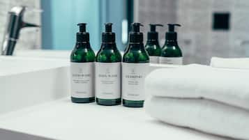 A bathroom with a white sink, green hand wash bottles, and a white towel.