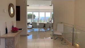 Ein modernes Interieur mit Glastrennwand, einer Sitzgelegenheit mit Ausblick und einem dekorativen Spiegel.