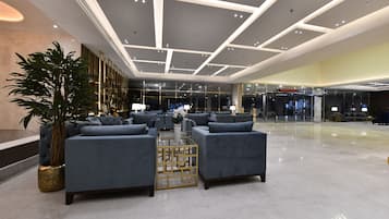 Um hall amplo com móveis modernos, uma planta em vaso grande e uma mesa de centro de vidro.