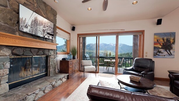 A spacious living room with a stone fireplace, leather furniture, and a balcony with mountain views. - Pet Friendly Home at Purgatory - Decks with Amazing Views - Steps to Lifts (Durango)
