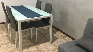 Ein Essbereich mit Tisch, Stühlen, einem gemusterten Boden und einem grauen Sofa.
