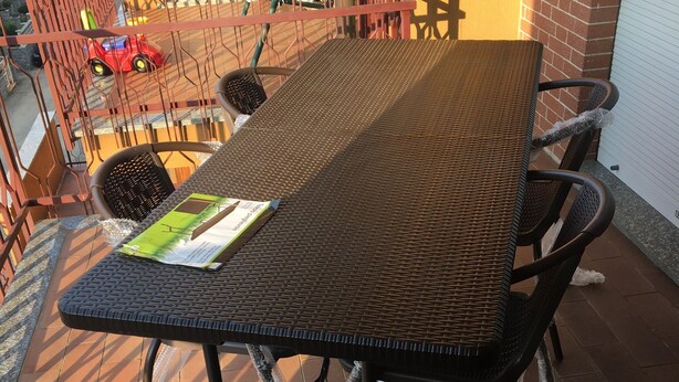 Ein Patio mit einem Metalltisch und Stühlen, einem roten Spielzeugauto und einer gelben Wand im Hintergrund.