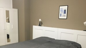 Ein Schlafzimmer mit einem großen Bett, einem Kleiderschrank und einem gerahmten Bild an der Wand.