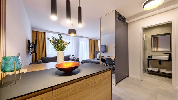 A modern kitchen with a wooden island, pendant lights, and a large window with curtains. - Wooden Studio/ Aircon/ Balcony/ City Center (Kraków-Śródmieście)