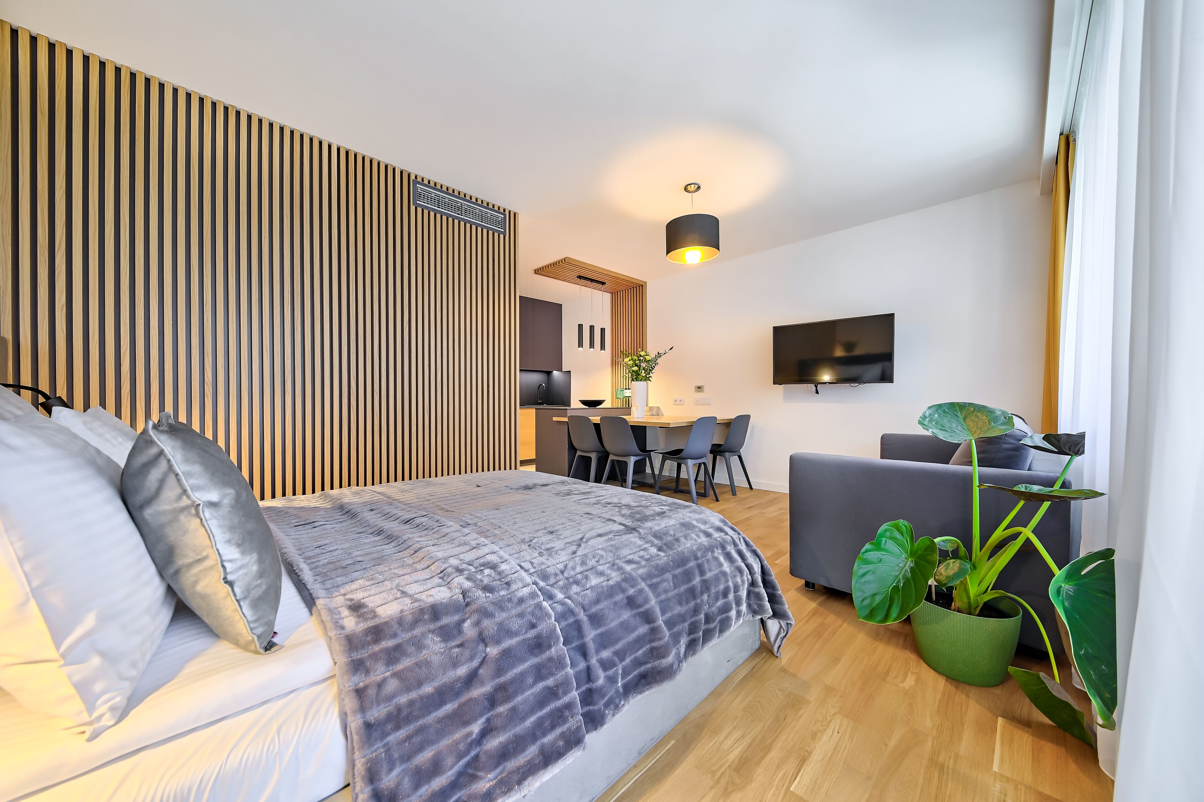 Een moderne slaapkamer met een bed, nachtkastjes, een bureau en een eethoek.
