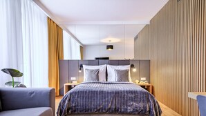 A modern hotel room with a large bed, a grey sofa, and wooden paneling on the walls. - Wooden Studio/ Aircon/ Balcony/ City Center (Kraków-Śródmieście)