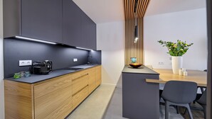 A modern kitchen with a wooden cabinet, a black countertop, and a built-in coffee maker. - Wooden Studio/ Aircon/ Balcony/ City Center (Kraków-Śródmieście)