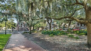 A brick pathway lined with trees and a garden area. - Pet friendly, Historic Garden Level w/ King Bed & No Stairs by Lucky Savannah (Savannah)