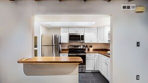 A modern kitchen with white cabinets, stainless steel appliances, and a wooden countertop. - Pet friendly, Historic Garden Level w/ King Bed & No Stairs by Lucky Savannah (Savannah)