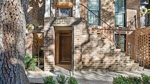 A brick building with a wooden door, a metal staircase, and a tree in the foreground. - Pet friendly, Historic Garden Level w/ King Bed & No Stairs by Lucky Savannah (Savannah)