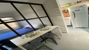 A compact kitchen with a white refrigerator, a small countertop, and a window with a view. - The building is right across from the beach, and the studio apartment has a wide view of it. (SP)