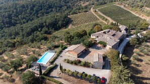 Vista aerea di una proprietà con piscina, edifici in pietra e vigneti.