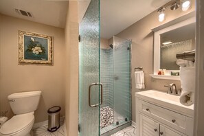 A bathroom with a toilet, a glass shower enclosure, a sink, and a mirror. - Ponderosa Barndominium Prd 2475 3 Bedroom Home by RedAwning (New Braunfels)
