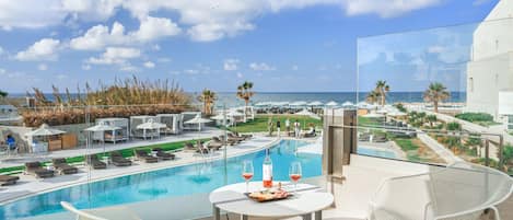 A balcony with a pool, lounge chairs, and a table with a bottle and glasses.