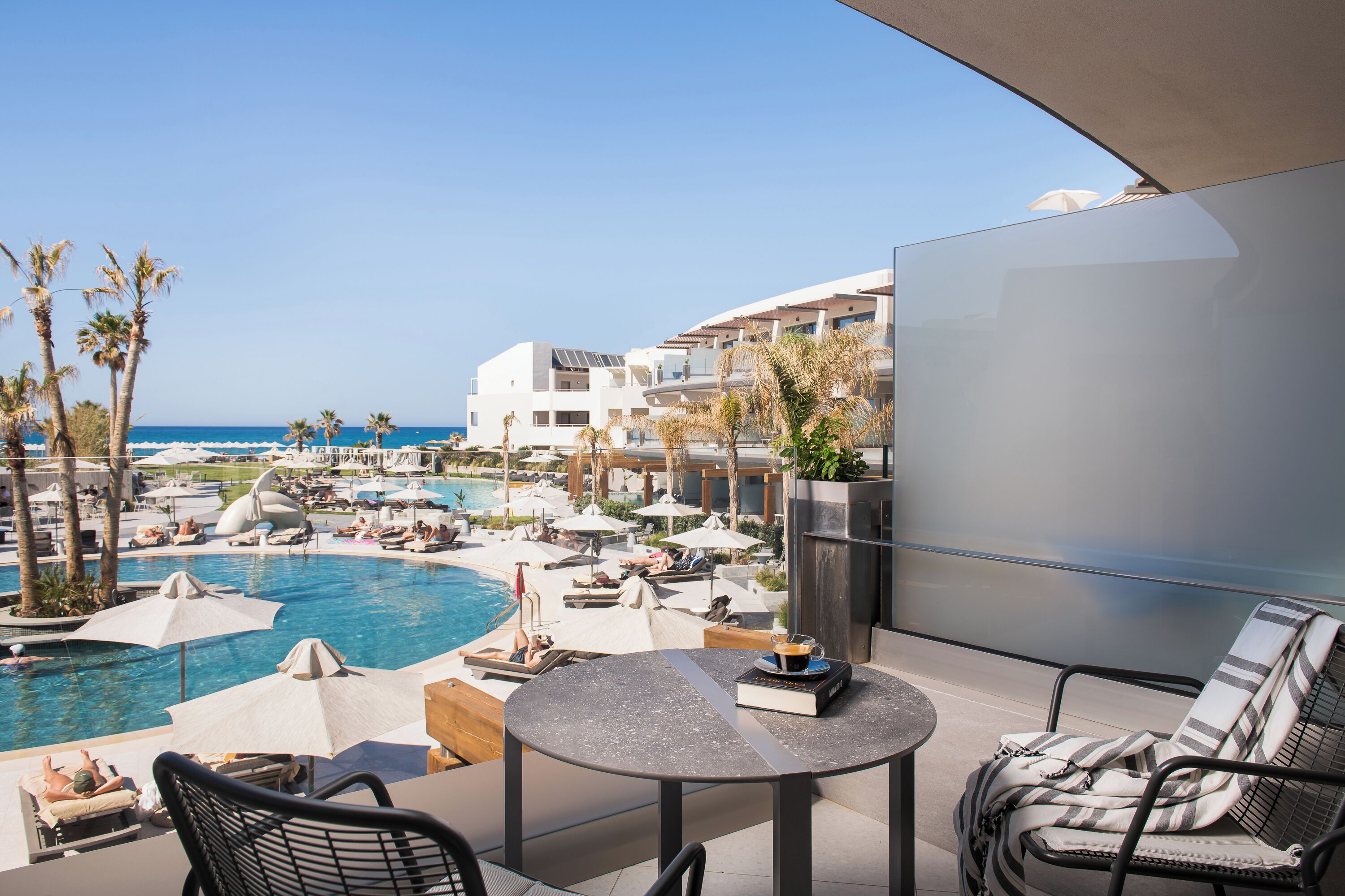 Un espace aménagé au bord de la piscine, avec des chaises longues, des parasols et une vue sur la mer.