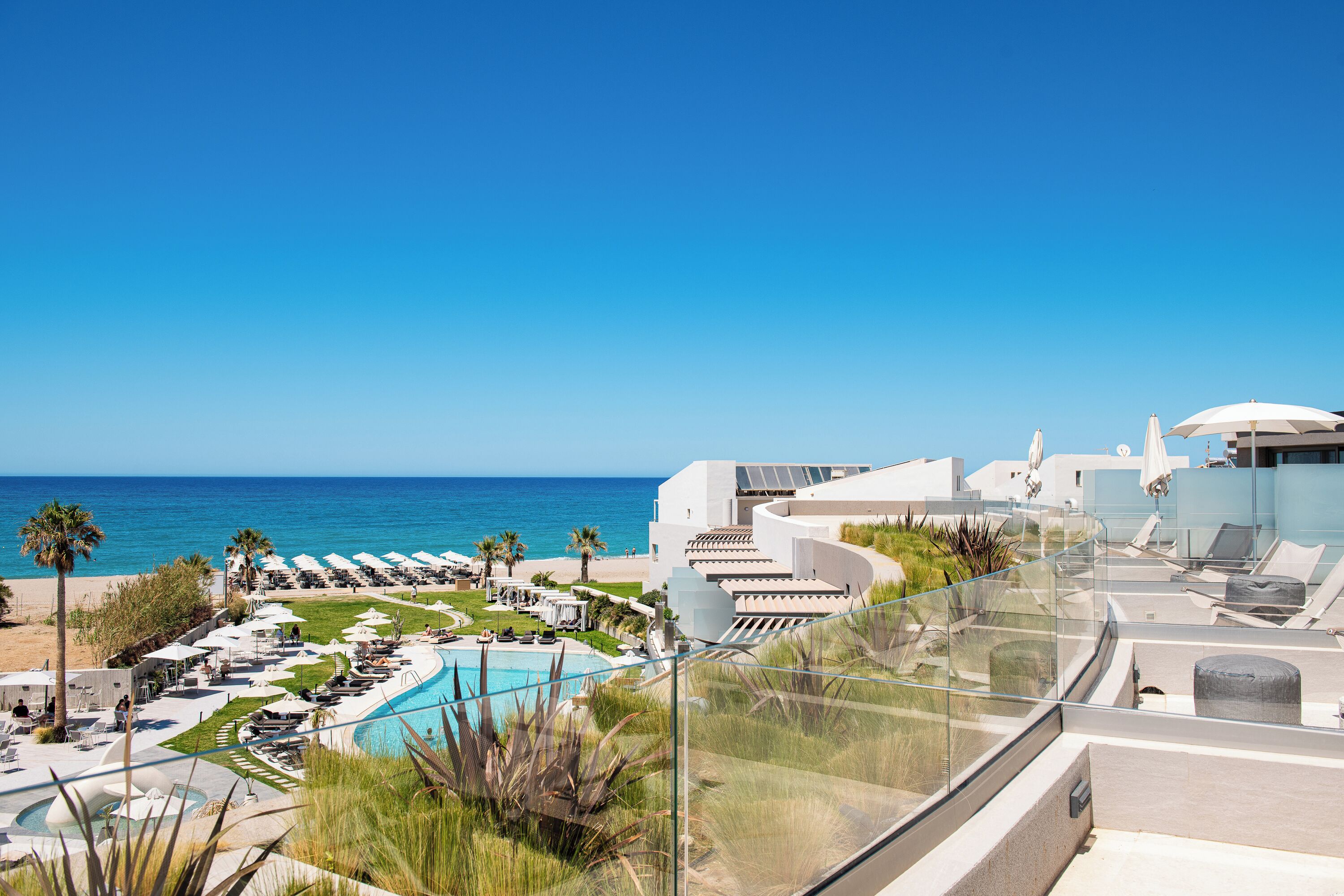 Un resort con piscina, sdraio e vista sull'oceano.