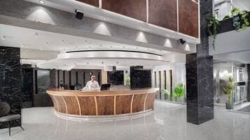 A modern reception area with a curved reception desk, marble walls, and a high ceiling with recessed lighting.