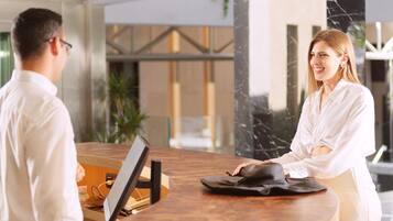 A reception desk with a computer monitor, a black bag, and a wooden counter.