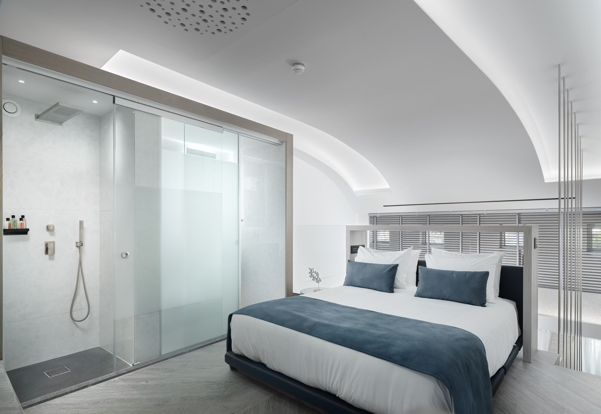 A modern bedroom with a large bed, a glass shower enclosure, and a minimalist design.