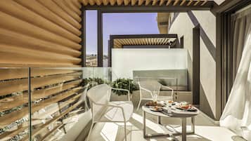 A modern balcony with a glass railing, a dining table with plates and glasses, and a view of the cityscape.