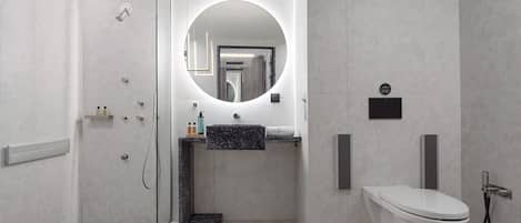 Een moderne badkamer met een douchecabine van glas, een ronde spiegel, een marmeren wastafel en een toilet.