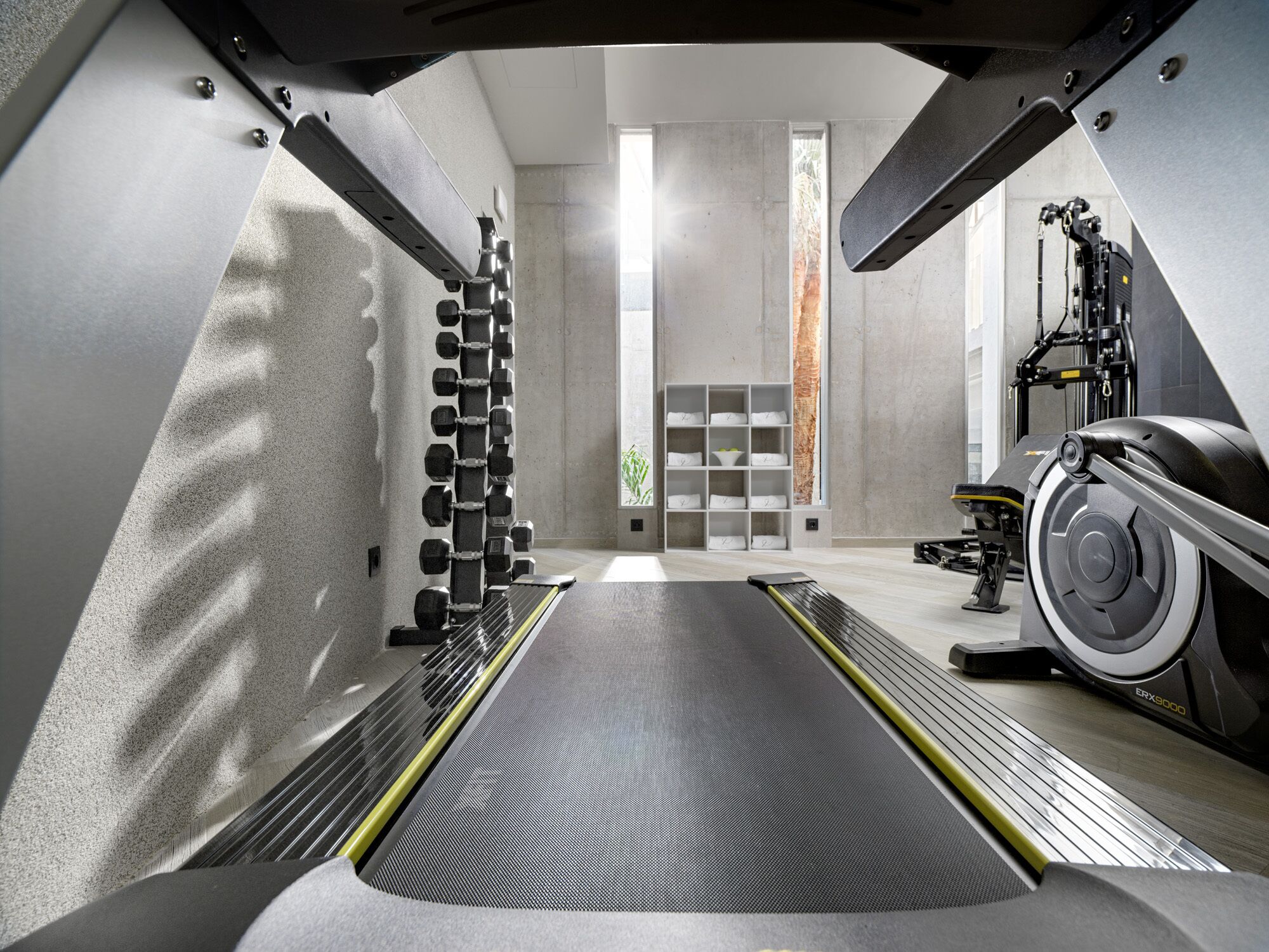 A modern gym with a treadmill, weight rack, and exercise equipment.