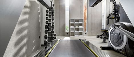 Ein modernes Fitnessstudio mit Laufband, Gewichtsbank und Trainingsgeräten.