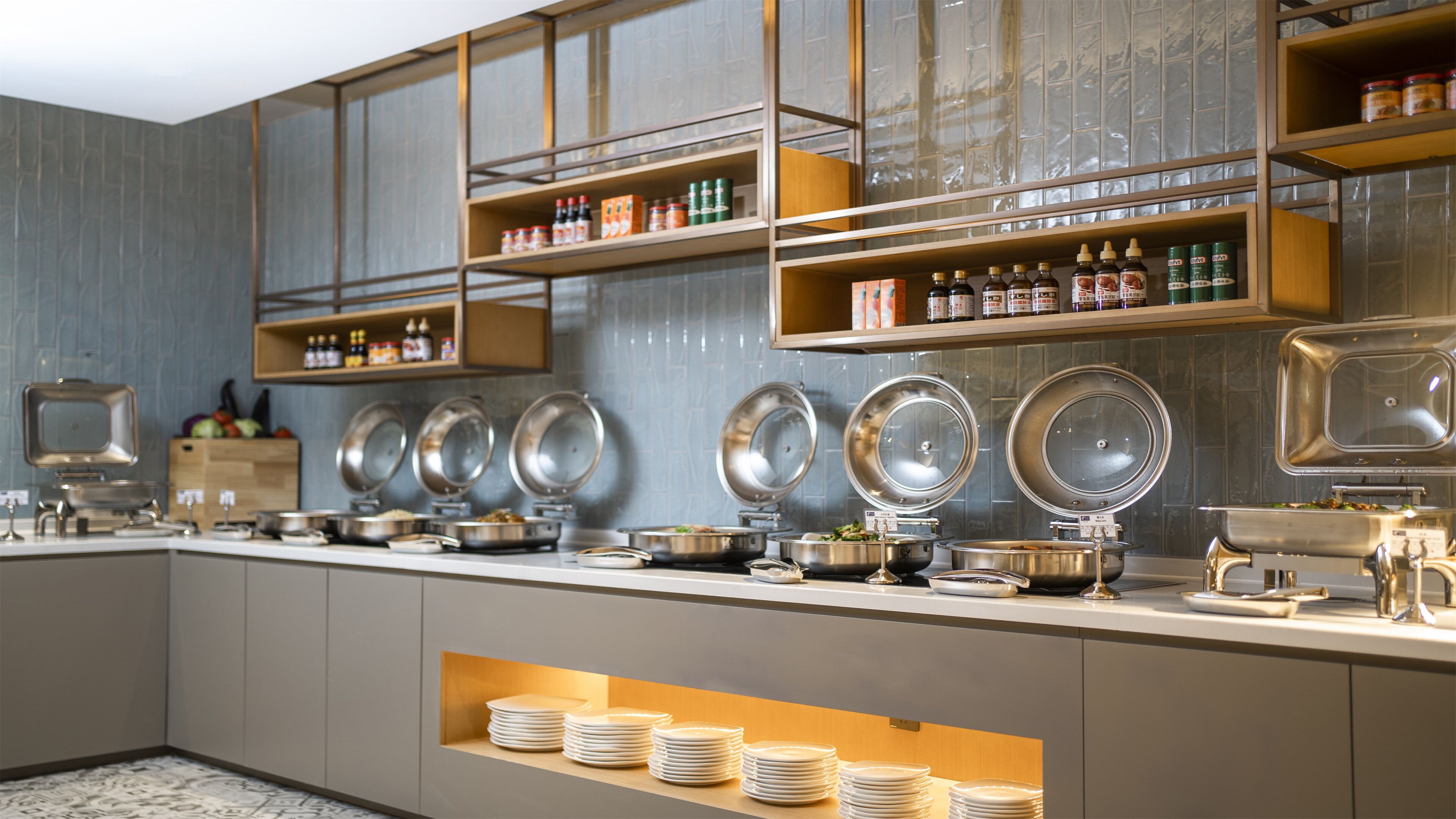 Montaje de bufé con varias estaciones de servicio, fuentes de acero inoxidable y una variedad de salsas y aderezos en estantes.