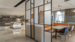 Une cuisine moderne dotée d’un îlot central, d’un coin repas avec une table et des chaises, et offrant une vue sur l’espace de vie grâce à une cloison.