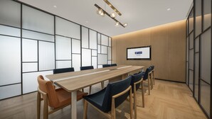 Une salle de conférence équipée d’une longue table, de six chaises, d’un écran de projection et d’un luminaire moderne.