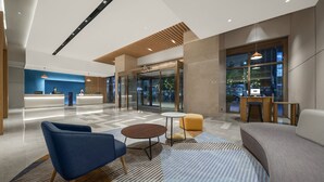 Un hall d’entrée moderne avec un comptoir d’accueil, un espace salon et de grandes fenêtres.