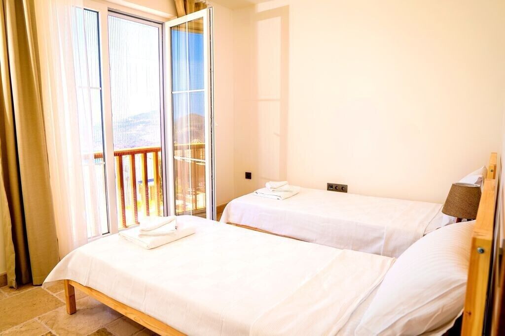 Une chambre d’hôtel avec deux lits, une porte-fenêtre coulissante donnant sur un balcon et un plancher en bois.