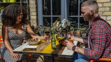 A dining table with a bottle of beer, plates of food, and a glass of red wine.