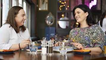Dos personas cenando en una mesa, con un menú, saleros y vasos de agua.