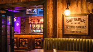 A bar area with a wooden interior, a neon sign, and a framed menu on the wall.