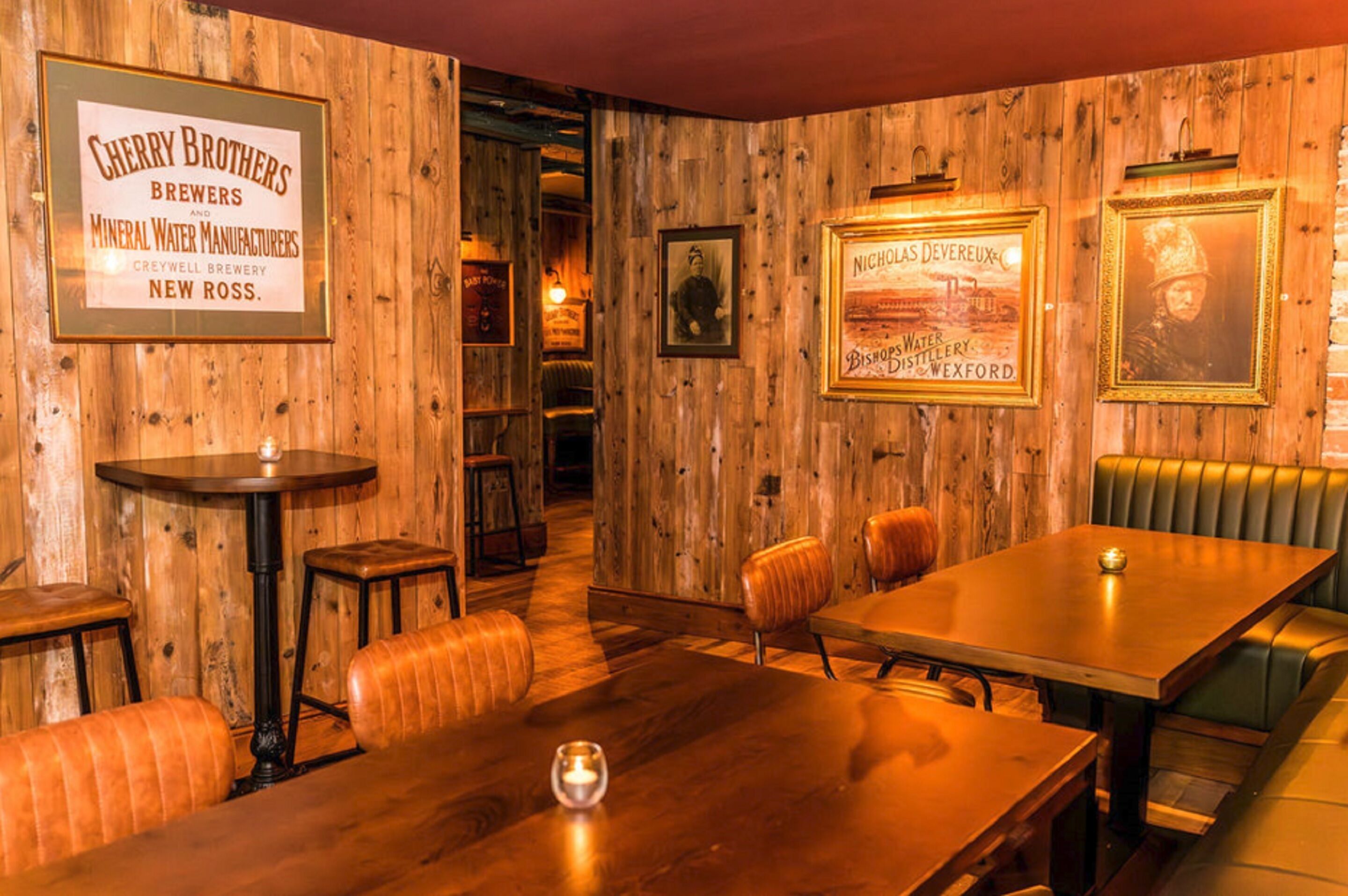 A rustic interior with wooden walls, a bar area, and framed historical posters.