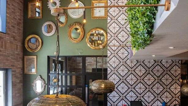 A restaurant with a green wall, patterned wallpaper, and hanging light fixtures.
