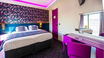 A modern bedroom with a bed, desk, and chair, featuring vibrant wallpaper and a window with a view.