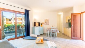Habitació d'hotel amb un llit, una taula petita, una menjadora i una cuina.