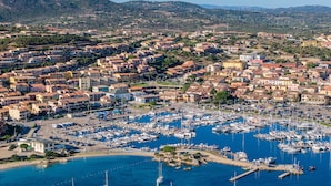 Un poble costaner amb un port esportiu ple de vaixells, envoltat d'edificis residencials.