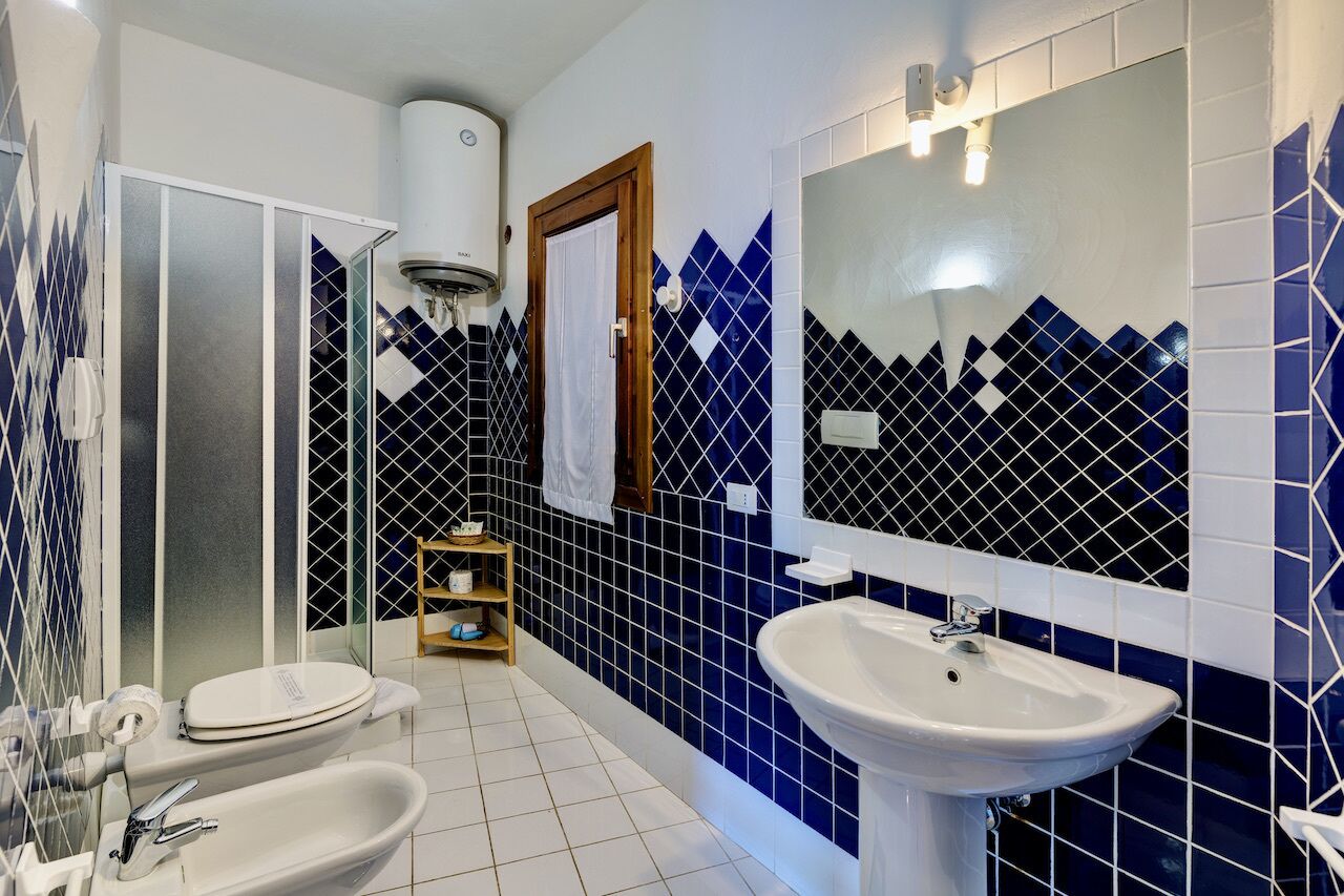 A bathroom with a white sink, a toilet, and a shower enclosure.