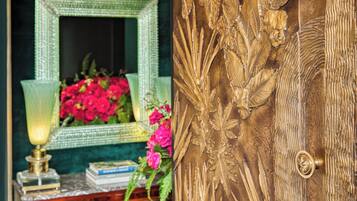A room with a green mirror, a lamp, and a floral arrangement.
