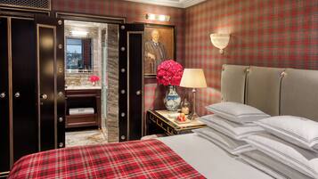 A hotel room with a bed, a nightstand, a lamp, a vase with flowers, a mirror, and a wardrobe.