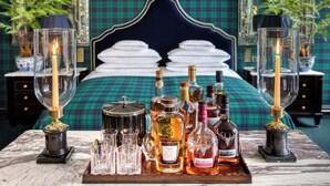 A luxurious bedroom with a large bed, a tray of liquor bottles, and candle holders. - 100 Princes Street (Edinburgh)